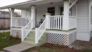 A two-story house with a porch, a front door, and a mailbox.
