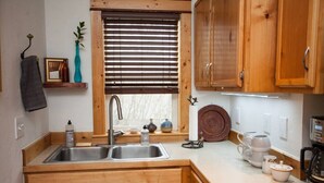 A compact kitchen with wooden cabinets, a double sink, and a coffee maker.