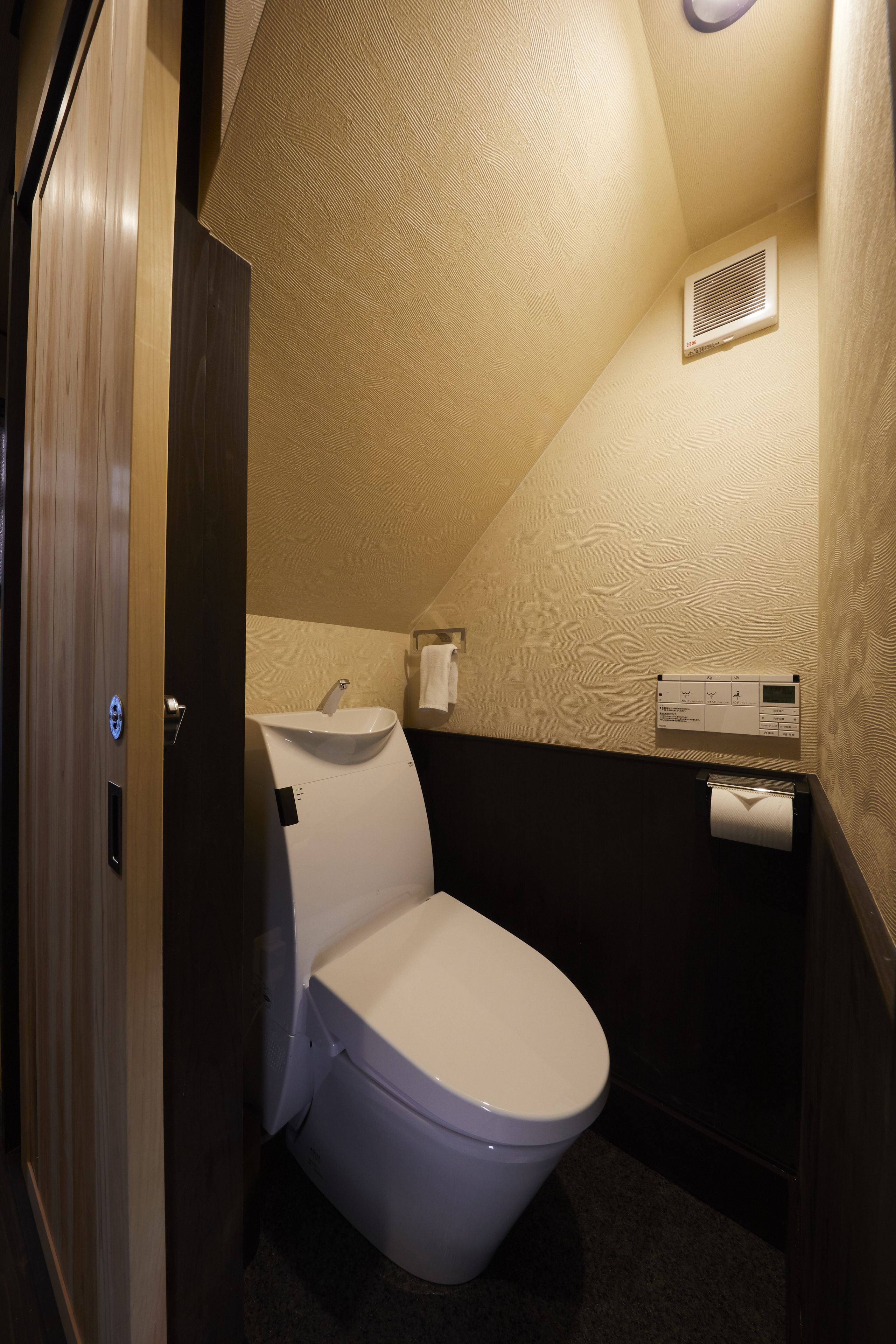 Un baño pequeño con inodoro, lavamanos y aire acondicionado de pared.