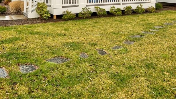 Une maison à deux étages dotée d’un porche, d’une zone d’entrée couverte et d’un petit jardin agrémenté de pas japonais.