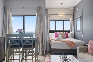 A bedroom with a bed, a desk, and a view of the sky. - Palace 2305 (Myrtle Beach)
