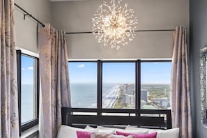 A bedroom with a large window, a bed, and a chandelier. - Palace 2305 (Myrtle Beach)