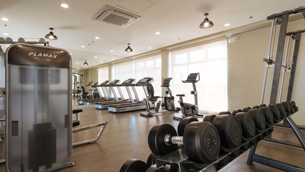 A gym with treadmills, a PLAMAX machine, and a rack of dumbbells. - RedDoorz Premium @ Vista Heights Legarda (Manila)