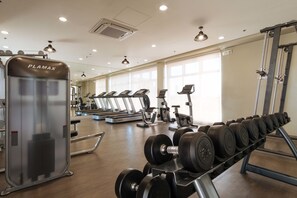A gym with treadmills, a PLAMAX machine, and a rack of dumbbells.