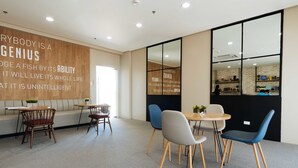 A modern, well-lit meeting room with a wooden wall featuring motivational quotes, a round table with chairs, and a large window with a view of the interior. - RedDoorz Premium @ Vista Heights Legarda (Manila)