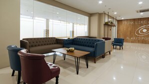 A modern lobby with a blue sofa, red armchair, and a wooden coffee table. - RedDoorz Premium @ Vista Heights Legarda (Manila)