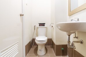 Une petite salle de bain avec des toilettes blanches, un lavabo et un miroir.