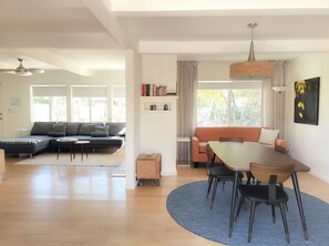 A modern living room with a sectional sofa, a dining table with chairs, and a ceiling fan. - Mid-Century Desert Oasis Private Pool & Spa (Palm Springs)