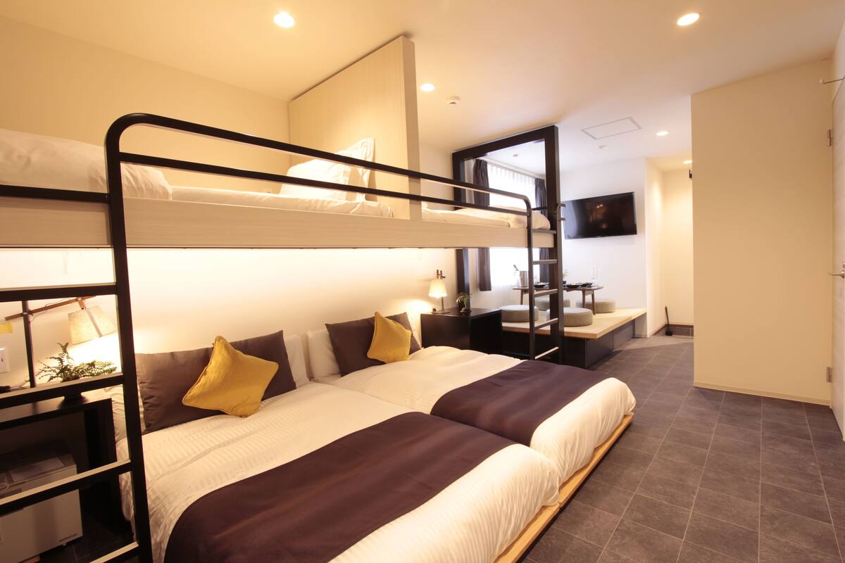 A bunk bed room with a desk, a mirror, and a TV.