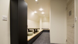 A hallway with a bench, a door, and a wall-mounted light fixture. - CHA-AN Hotel Ueno (Tokyo)