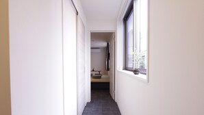 A narrow hallway with a window on the right, leading to a room with a bed and a small table. - CHA-AN Hotel Ueno (Tokyo)