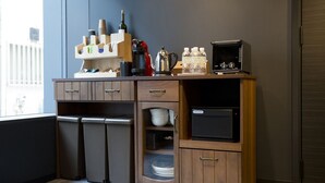 A compact kitchen with a refrigerator, microwave, and wooden cabinets. - CHA-AN Hotel Ueno (Tokyo)