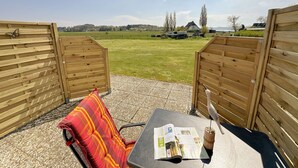 Une terrasse en bois avec une table et une chaise, un livre et un chapeau de paille.