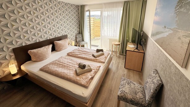 Une chambre d’hôtel avec un grand lit, un bureau avec une télévision, une chaise et une vue sur l’extérieur.