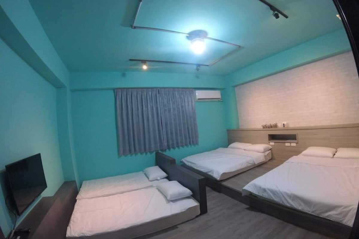 A room with three single beds, a flat-screen TV, and a ceiling fan.