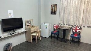 A compact living space with a TV, wooden desk, two chairs with Union Jack designs, a small refrigerator, and a waste bin. - Dan Blue B&B (Magong)