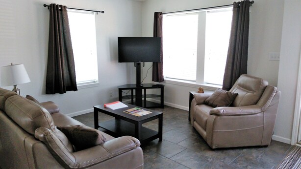 A living room with a flat-screen TV, two leather sofas, a coffee table, and a lamp.