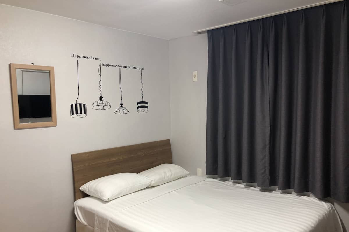 A bedroom with a bed, a mirror, and a wall decal with hanging lamps.