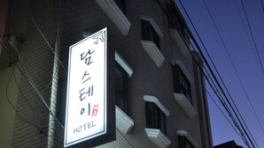 Un hôtel avec une enseigne dans une langue étrangère, une façade en briques et un vélo garé devant.