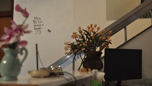 Un bureau avec un écran d’ordinateur, un vase rempli de fleurs et un mur orné d’une citation inspirante.