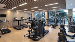 Un gimnasio con cintas de correr, elípticas y estaciones de pesas, con pisos de madera y ventanas amplias.