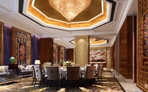 Quarto de hotel luxuoso com área de jantar, incluindo uma mesa redonda, várias cadeiras e um lustre.