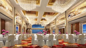 Un salón de banquetes con sillas blancas, mesas redondas y candelabros.