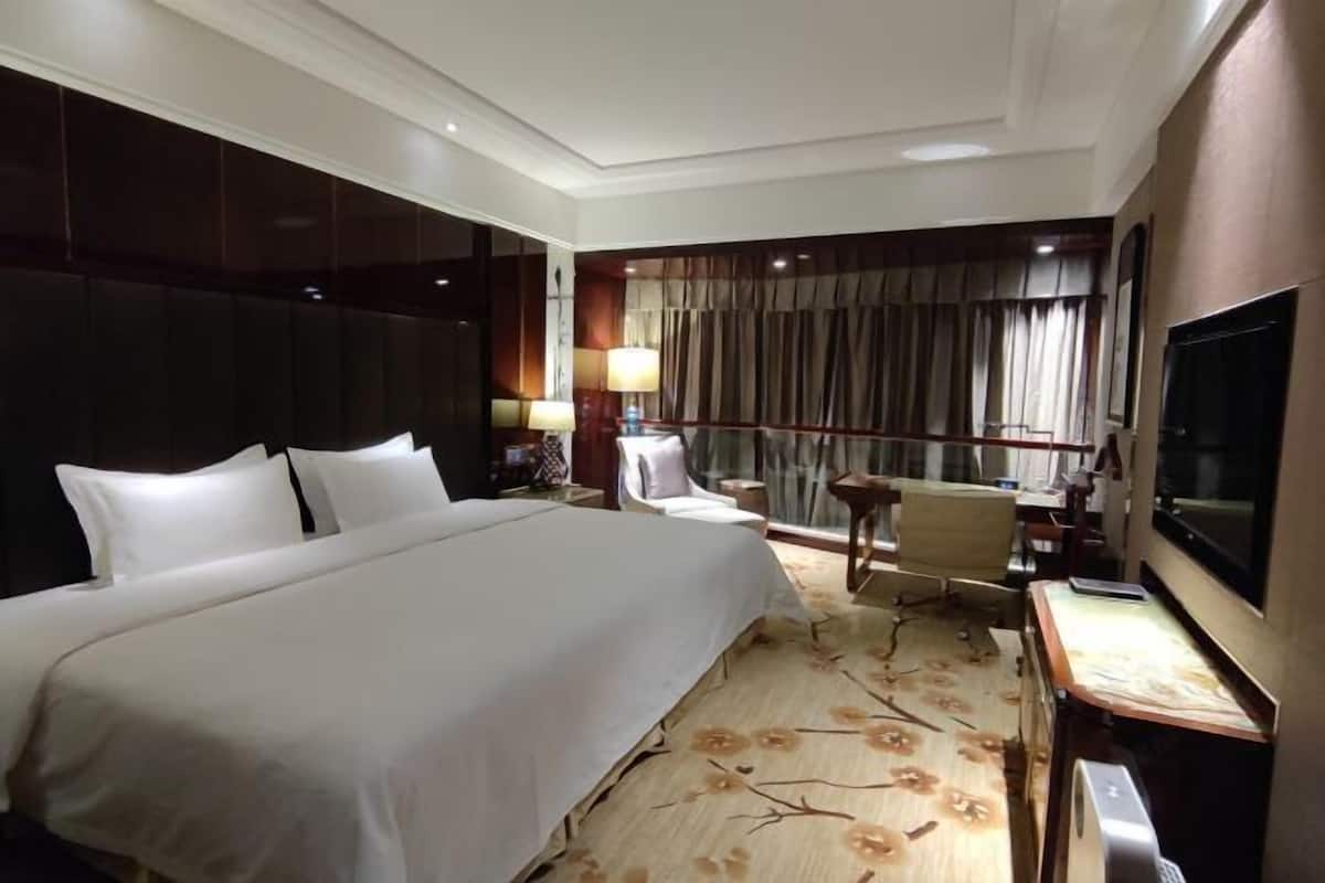Relax in comfort with a large bed against a stylish headboard, a flat-screen TV, and a cozy reading nook.