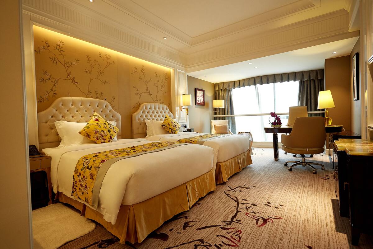A hotel room with two beds, a desk, and a chair.