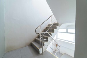 A modern staircase with metal railings and a view of the sky through a window. - RedDoorz Plus @ Roxas Street Davao (Davao)