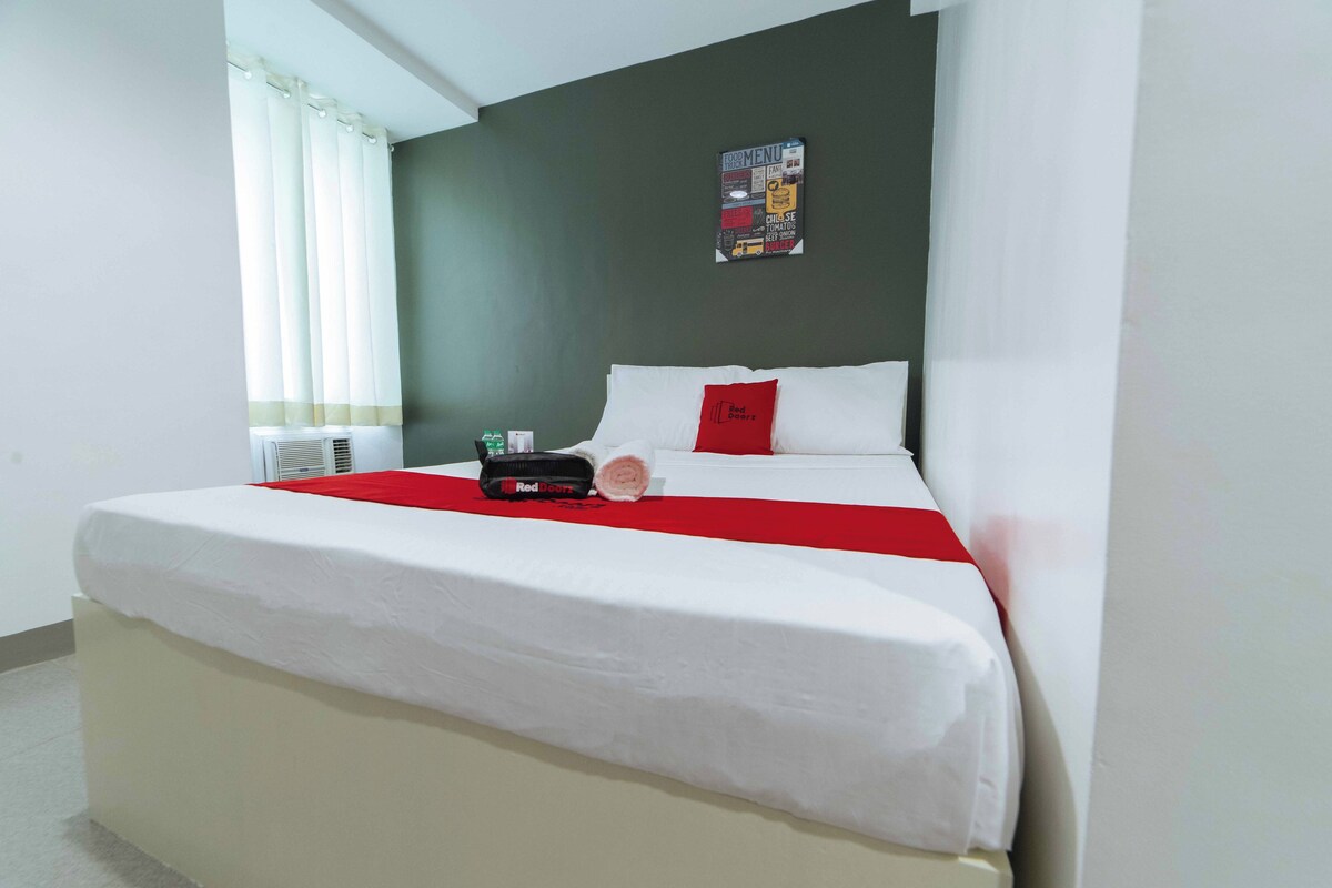 Hotellihuone, jossa on sänky, seinälle kiinnitetty ruokalista ja ikkuna, jossa on verhot.