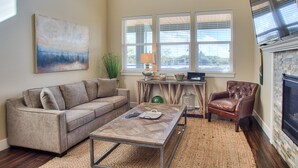 A living room with a sofa, armchair, coffee table, and fireplace. - Whale of a Tale - Oyhut Bay Seaside Village (Ocean Shores)