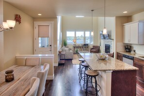 Una cocina moderna con una isla grande, taburetes de bar y un comedor con mesa y sillas de madera.