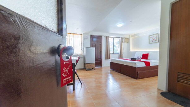 A hotel room with a bed, a desk, and a kitchenette.