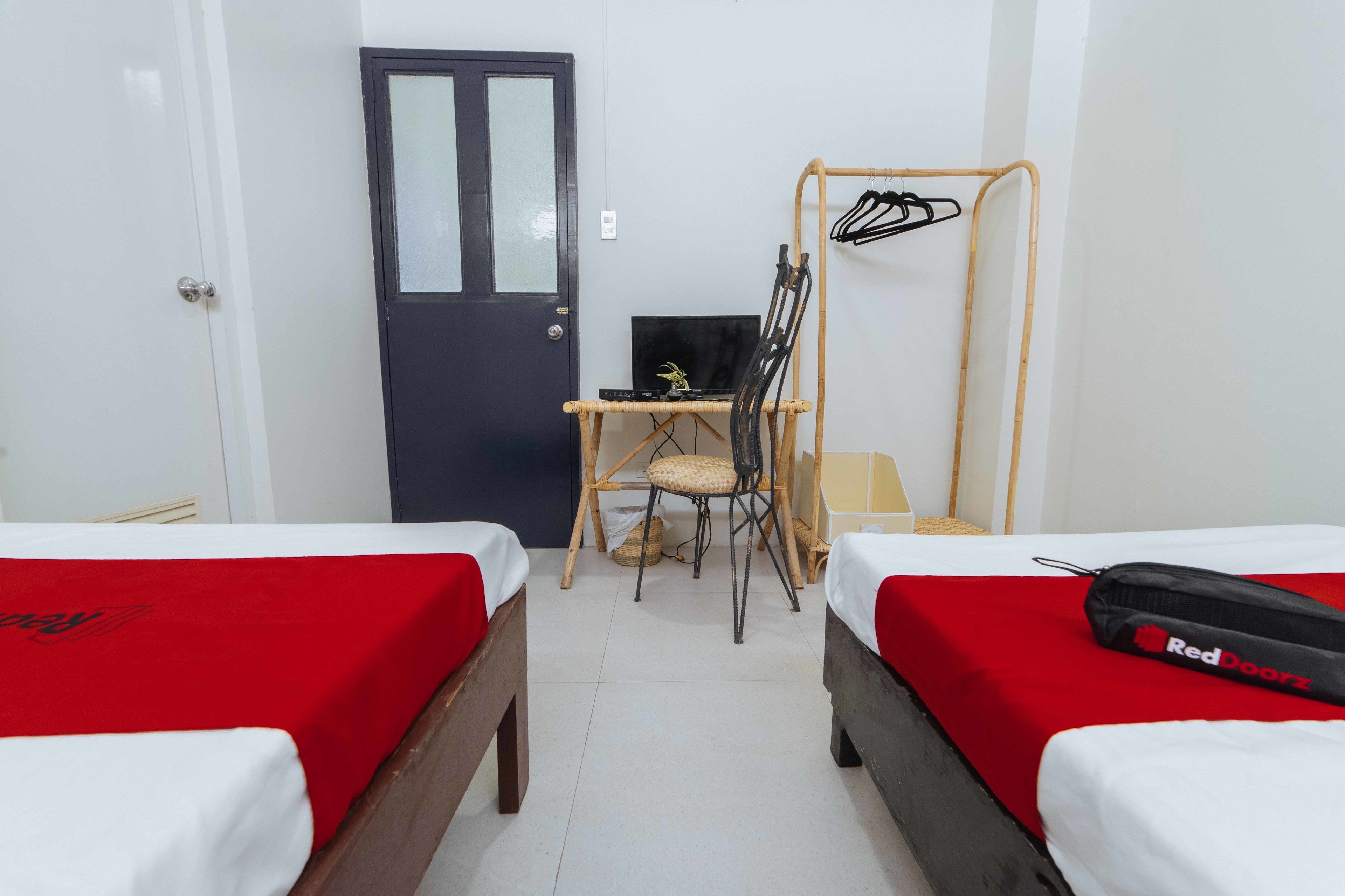 Une chambre d’hôtel avec deux lits, un bureau avec un ordinateur, une chaise et un porte-manteau.