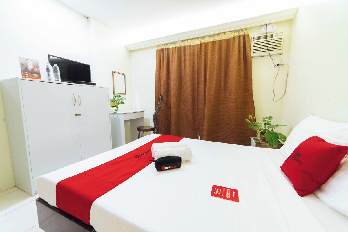 A hotel room with a bed, a desk, a wardrobe, and a window with curtains.