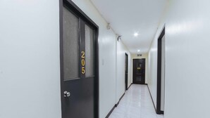 A hallway with a door marked 205, white walls, and a tiled floor.