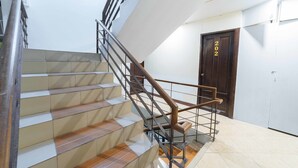 A staircase with a wooden handrail and metal balusters, leading to a room with a white door marked "202".