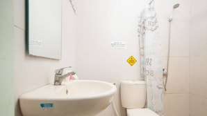 A bathroom with a sink, toilet, and shower curtain. - RedDoorz @ Raya Tidar (Malang)