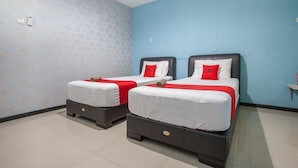 A hotel room with two beds, each with a red and white bedspread and matching pillows. - RedDoorz @ Raya Tidar (Malang)
