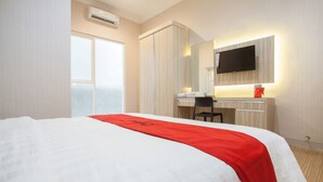 Habitación de hotel con cama, escritorio, silla, televisor montado en la pared y equipo de aire acondicionado.