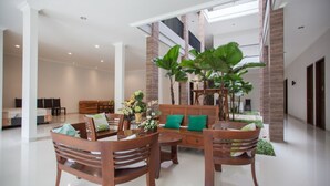 Un vestíbulo espacioso con techo alto, muebles de madera y una gran planta de interior.