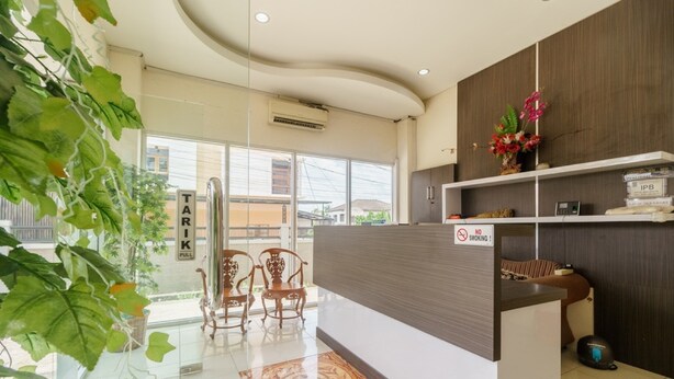 A reception area with a modern design, including a reception desk, chairs, and a view of the outside. - RedDoorz @ Jalan Jenderal Sudirman Palembang 2 (Palembang)