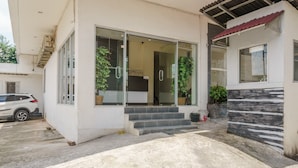 A modern house with a glass door entrance, a small staircase leading to the door, and a car parked in the driveway. - RedDoorz @ Jalan Jenderal Sudirman Palembang 2 (Palembang)
