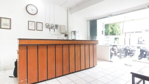 A reception desk with a clock, framed certificates, and a window with a view of parked motorcycles. - RedDoorz near Kranggan Tugu Jogja (Yogyakarta)