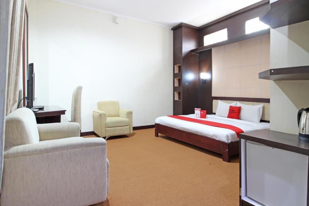 Une chambre d’hôtel avec un lit, une chaise, un bureau et un téléviseur.