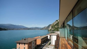 Un edificio moderno con fachada de vidrio que da a un lago y montañas.