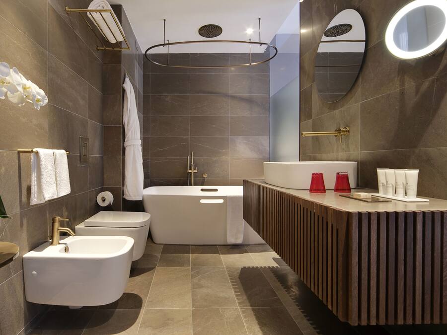 Ein modernes Badezimmer mit integriertem Bidet, Toilette, Badewanne und Waschtisch mit Spiegel und Handtuchhalter.