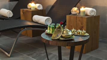 A spa area with reclining chairs, a small round table with decorative items, and candles.