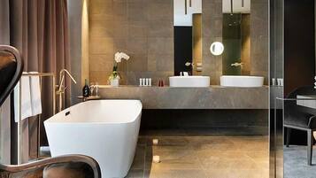 A modern bathroom with a large bathtub, two sinks, and a vanity with a mirror.